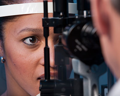 Ophthalmologist uses slit lamp to examine woman's eyes