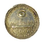 A silver circular coin-shaped object with a human eye and eyebrow above a cityscape. With German words bordering the object and underneath the cityscape.  